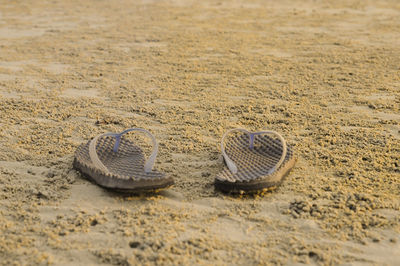 Close-up of flip-flop on sand at beach