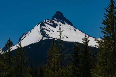 Low angle view of snowcapped mountains against blue sky