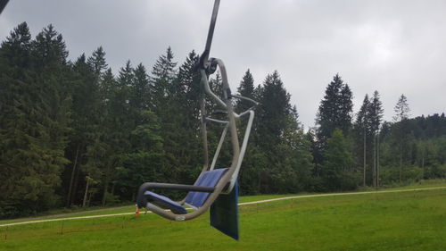 Empty swing in park against sky