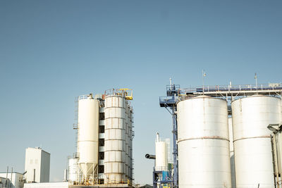 Low angle view of factory against clear blue sky