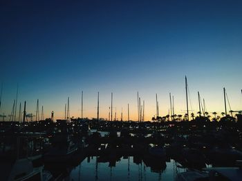 Sailboats moored at harbor against clear sky