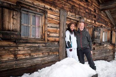 Portrait of people standing against log cabin during winter