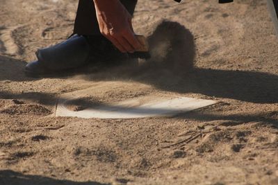 Low section of man cleaning home base during match