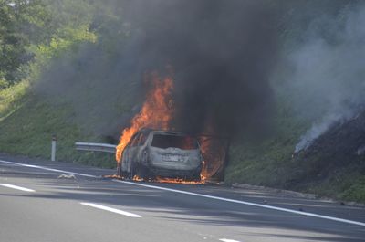 Burnt car at roadside by hill