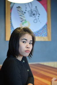 Portrait of beautiful young woman sitting at wooden table in cafe