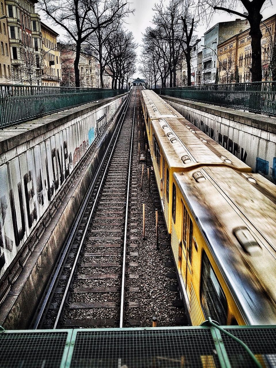 railroad track, rail transportation, transportation, built structure, architecture, public transportation, building exterior, diminishing perspective, the way forward, vanishing point, city, railway track, railroad station, railroad station platform, tree, high angle view, day, travel, outdoors, bare tree