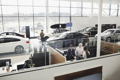 Car salesperson talking with customers at desk in showroom