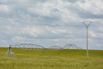 Electricity pylon on field against sky