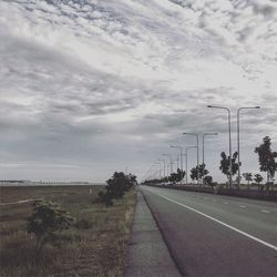 Empty road against cloudy sky