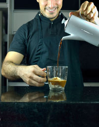 Midsection of mid adult man preparing coffee in kitchen