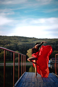 Side view of woman standing by railing against sky