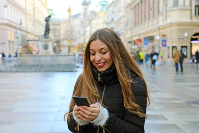 Young woman using mobile phone in city