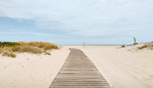 Boardwalk leading towards beach against sky