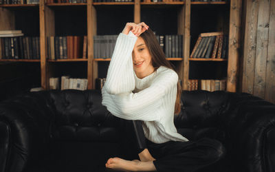 Portrait of young woman sitting on chair at home