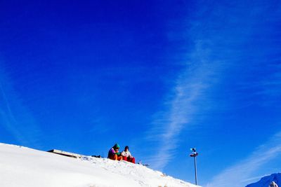 Low angle view of people against blue sky