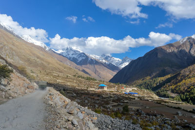 Scenic view of road by mountains against sky. 