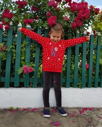 Full length of girl standing by red flowers