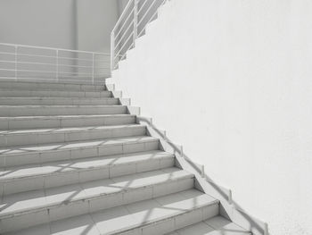 White exterior of outdoor staircase with railing.sunlight and shadow on stone steps. urban geometry.