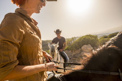 Man and woman riding horse on field