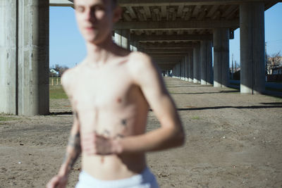 Midsection of shirtless man standing in city