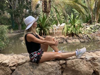 Side view of young woman sitting on rock
