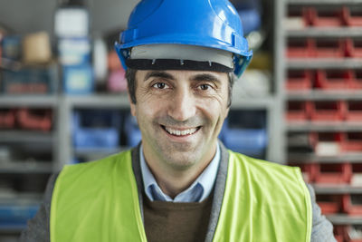 Portrait of happy mature manual worker wearing hardhat in factory