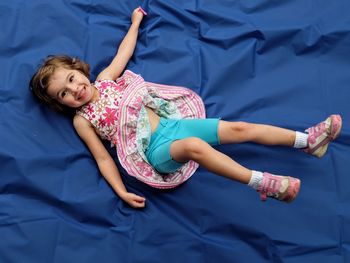 Portrait of cute girl lying on blue sheet