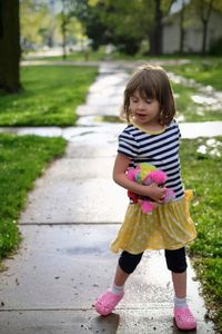 Full length of girl holding toy while standing on walkway at park during rainy season