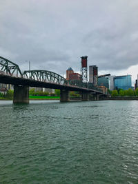 Bridge over river against sky in city