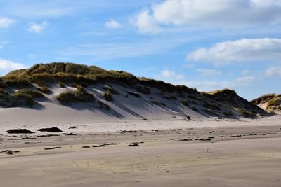 Scenic view of sand dunes and beach against sky