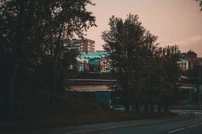Road by buildings in city against sky
