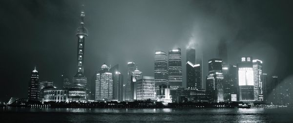 Low angle view of illuminated oriental pearl tower and cityscape against sky