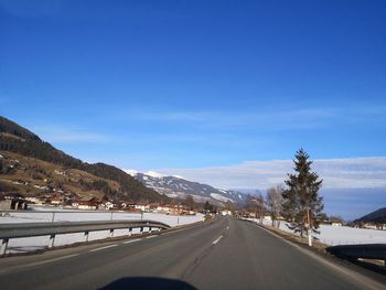 Road by mountains against blue sky