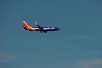 Low angle view of airplane flying against clear blue sky