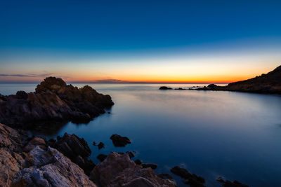 Scenic view of sea against sky at sunrise with rocks in the foreground