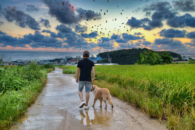 Full length of woman with dog on street against sky