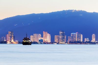 Sea by cityscape against sky