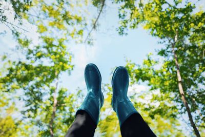 Low section of person with rubber boots against trees in summer