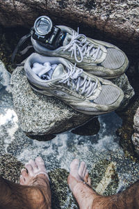 Feet of man standing on rock with shoes and camera