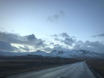 Road by mountains against sky during winter