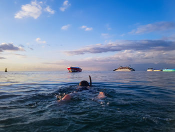 People swimming in sea against sky