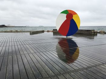 Multi colored umbrella on pier over sea against sky