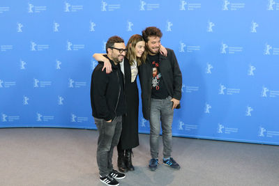 Full length of young couple standing against blue wall