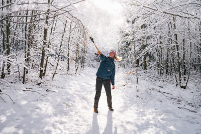 Full length of woman standing while playing with trees on snow covered land