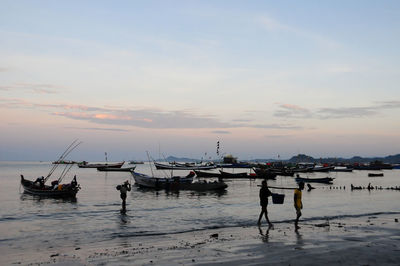 Boats moored in sea against sky during sunset