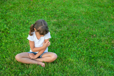 Rear view of woman sitting on grassy field