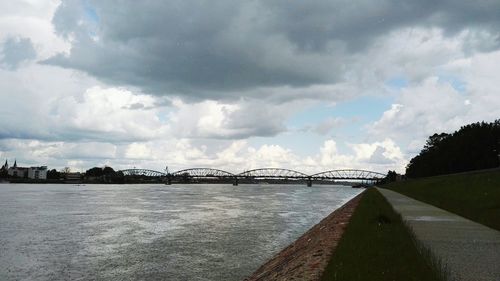 Bridge over river against cloudy sky