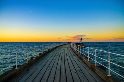 View of pier on calm sea at sunset