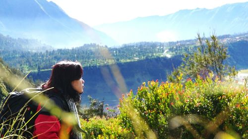 Young woman amidst plants on mountain against sky
