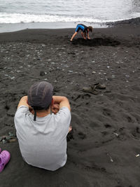 Rear view of men sitting on beach